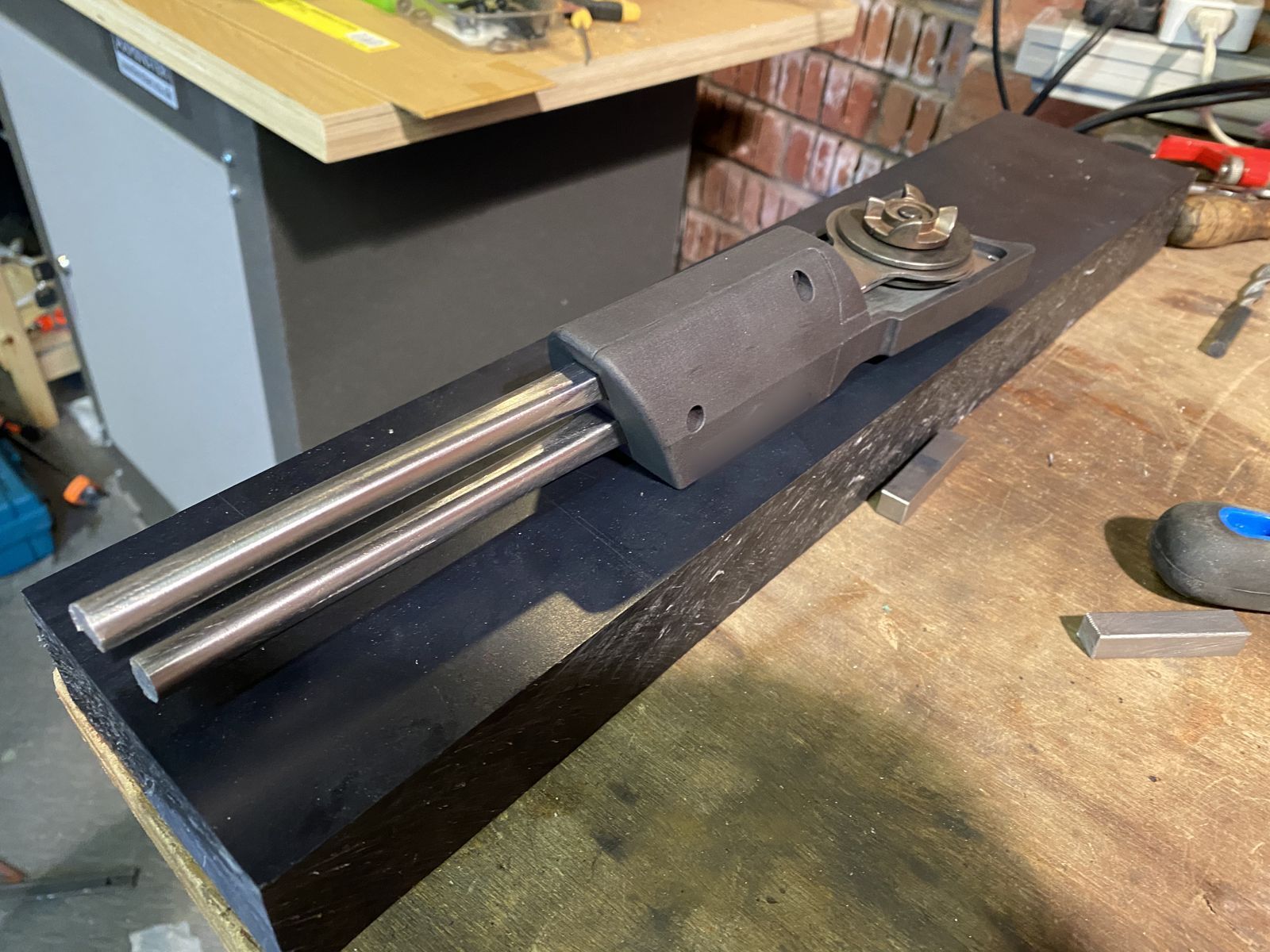 Prototype housing mounted on two steel guide rods on a workbench